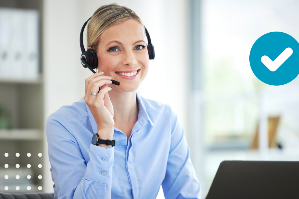 A smiling customer service representative wearing a headset and sitting at her desk, ready to provide on-call support to assist callers.
