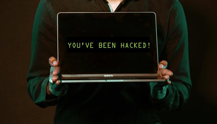 Person holding laptop that says "you've been hacked!"