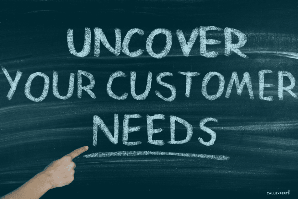 Hand pointing to a chalkboard message that reads "uncover your customer needs.